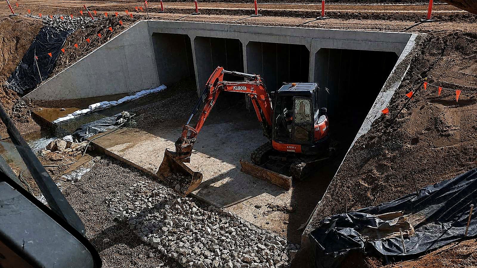 AreeCivil Constructions excavation at a concrete culvert Kubota excavator working inside a box culvert, placing rock from the cab of a second machine